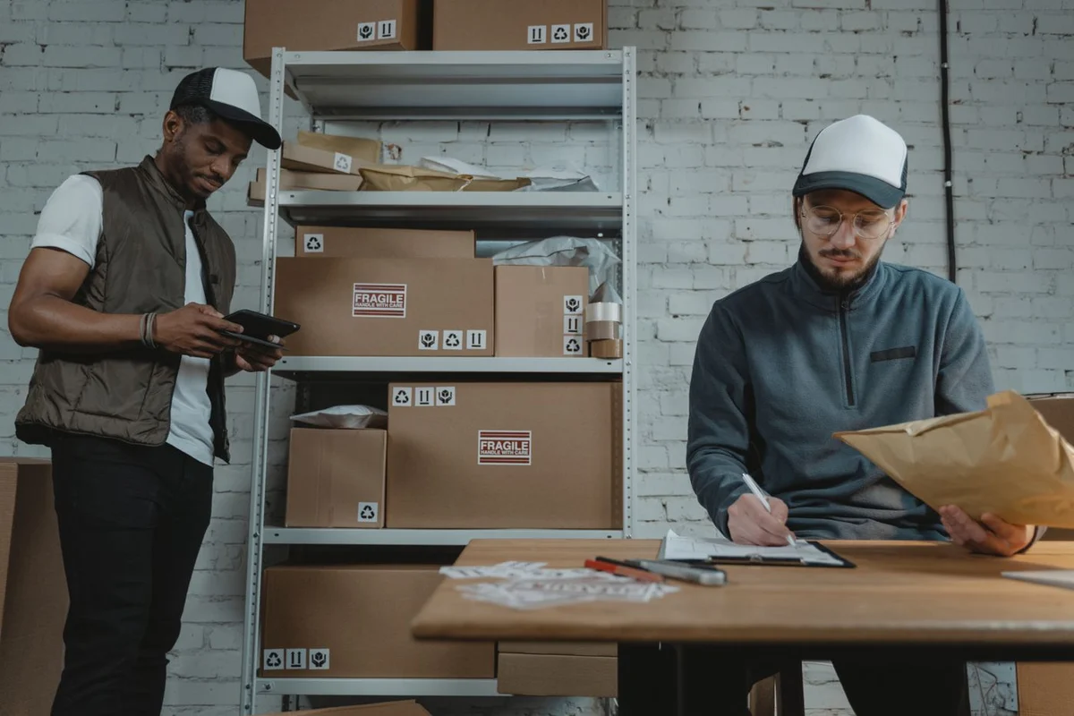 Two staff checking and packing customer orders in an organised stockroom